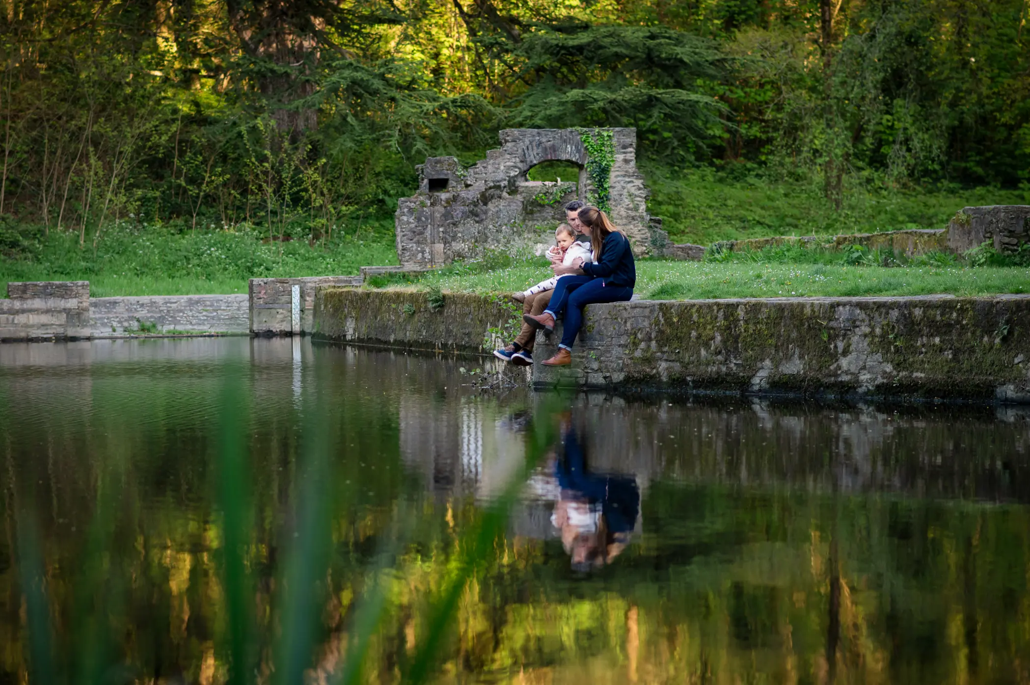 photo d’un couple et de leur fille, assis sur un muret au bord du gesvres.