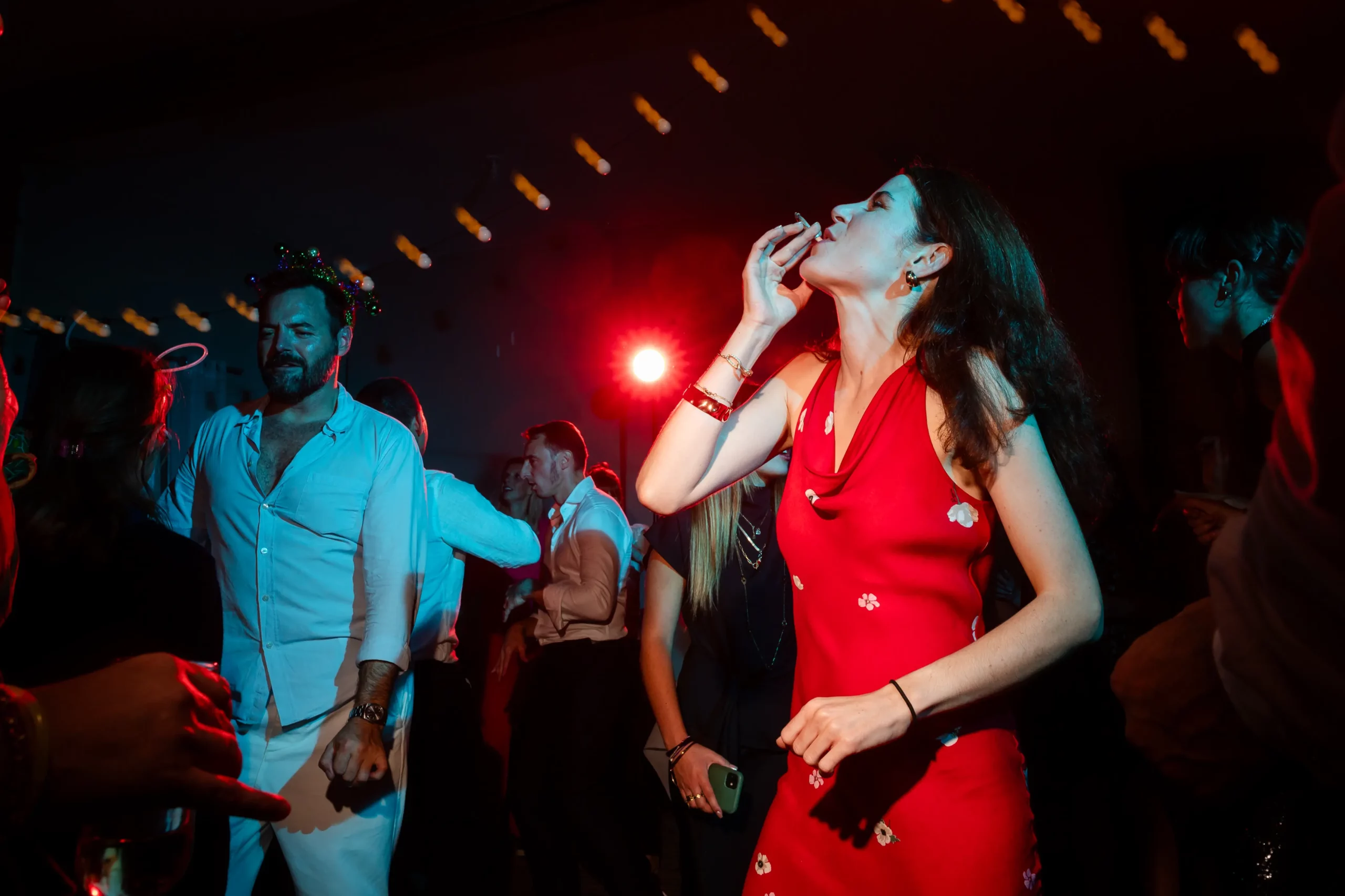 reportage mariage pendant la soirée, utilisation de flashs bleu et rouge, une invitée qui fume en premier plan