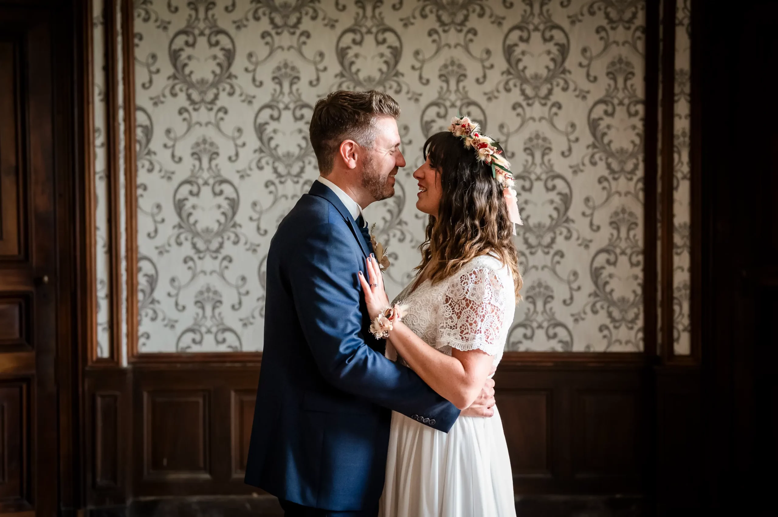 mariage-firstlook-chateau-de-la-roche photographie prise pendant la séance du firstkook au château de la Roche à Couffé. la scène se déroule à l'intérieur du château, les deux mariés se regardent en souriant, en fond il y a une jolie tapisserie