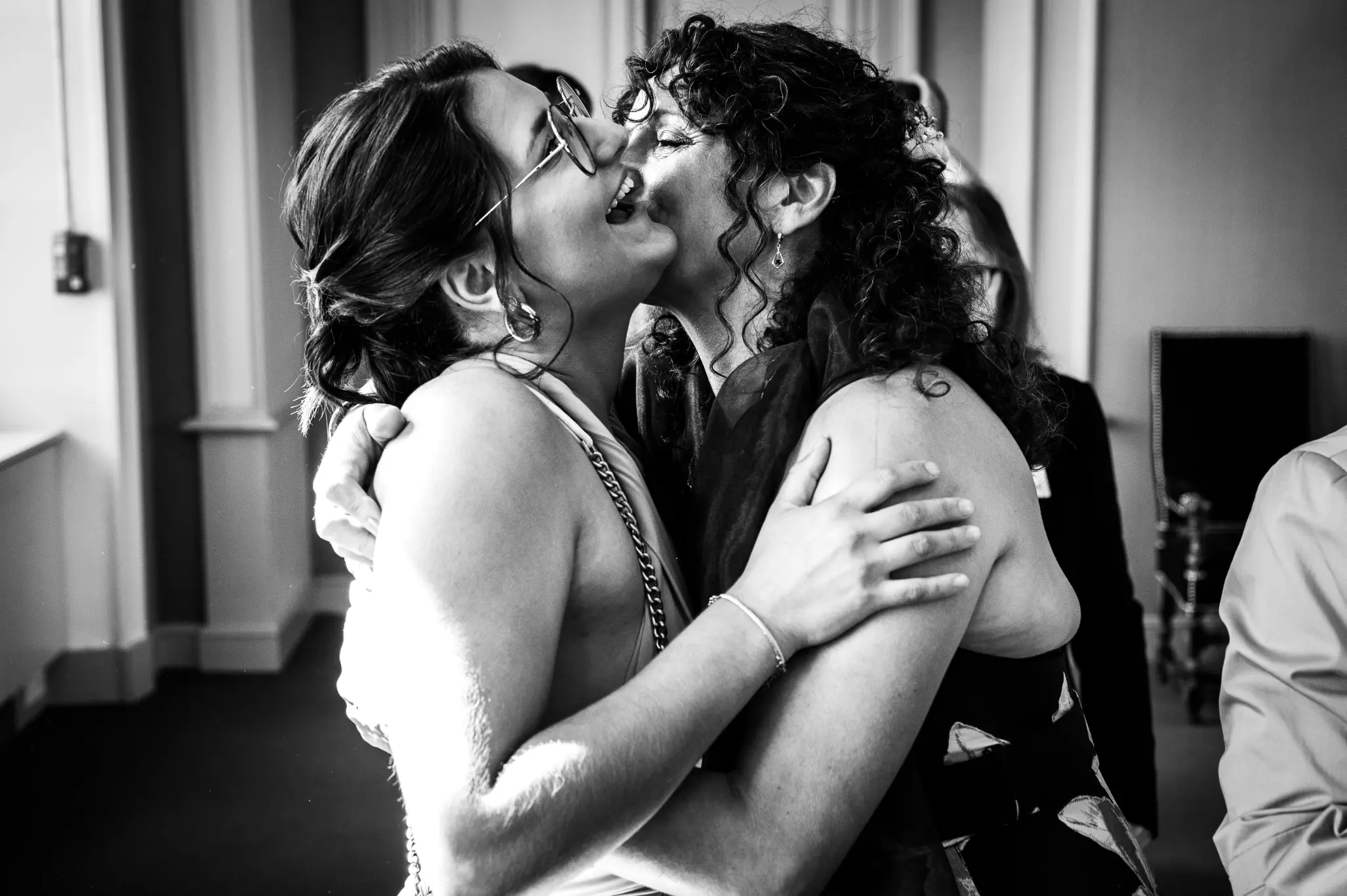 photographe-mariage-ceremonie-civile photographie prise dans la mairie d'Angers, la méman de la mariée embrasse sa fille qui est aussi la témoin. elles sont toutes les deux très souriantes et amusées de la situation