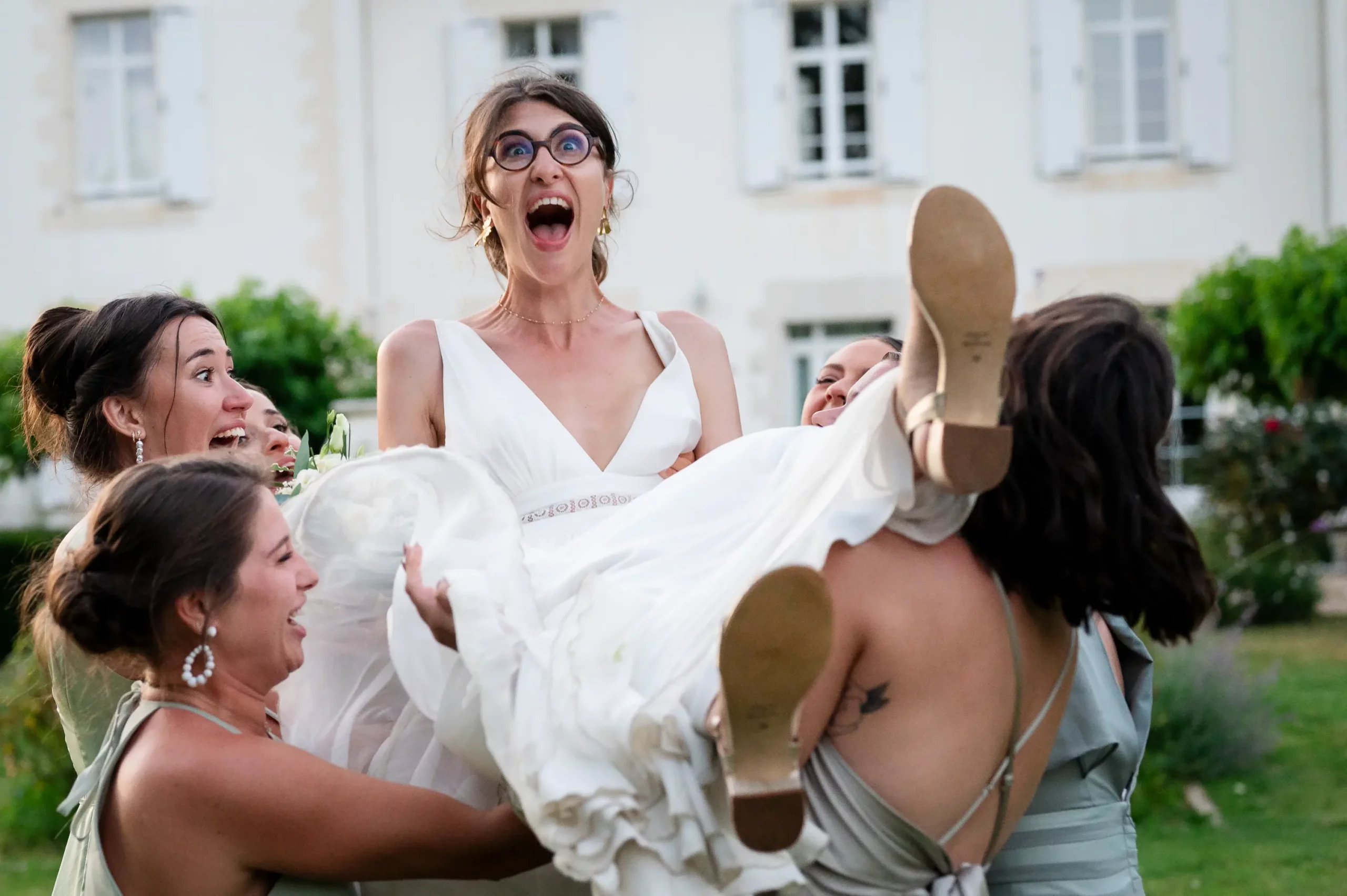 photographe-mariage-pornic-lance-mariee photographie prise au domaine de la pinelais, pendant le cocktail. les invitées portent la mariée, la fond sauter! la mariée fait un grand cri de joie