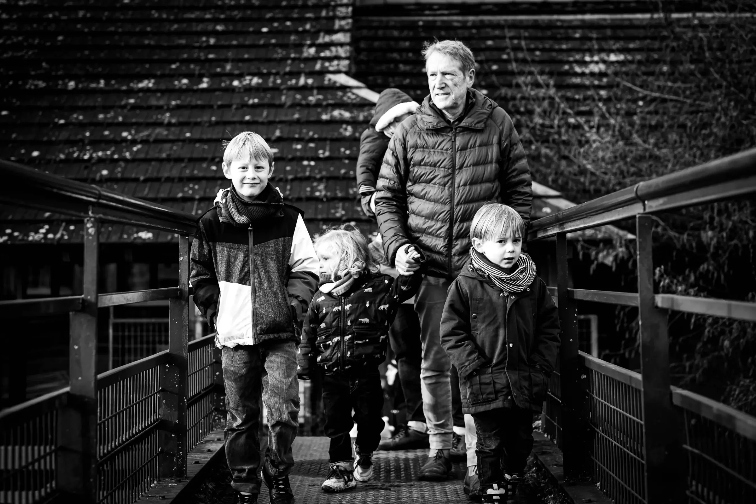 photographie-famille-grand-père offrir un repotage photo, comme la démarche de ce couple de grands parents, qui a souhaité un reportage avec leur famille à noël. cette photo montre le grand père avec ses petits enfants sur la passerelle de l'île de Versailles à Nantes
