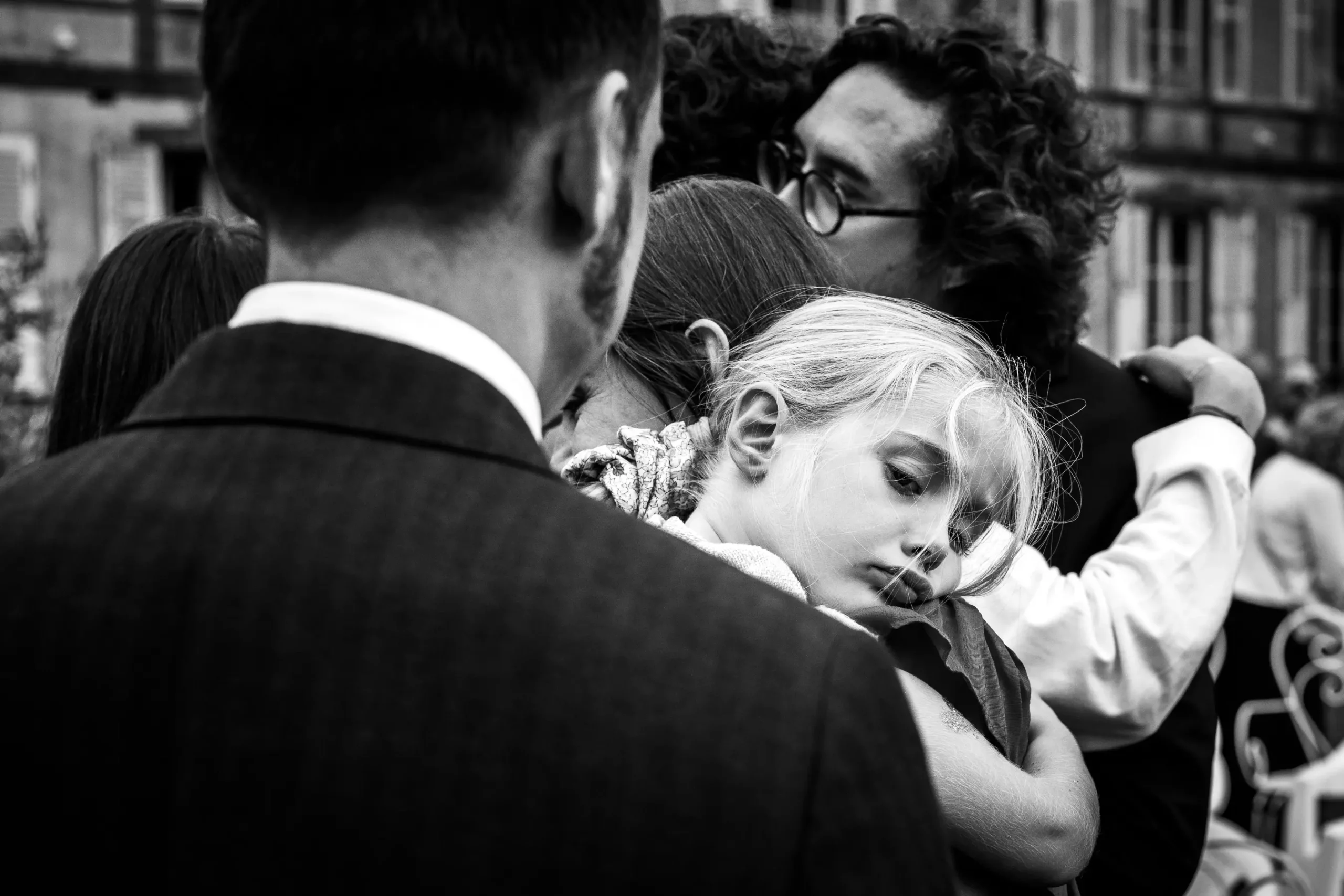 photojournalise-de-mariage-spontaneite-enfant lors du cocktail d'un mariage les invités rigolent en seond plan et en premier plan on voit la mariée en grand discussion, cette photo est en noir et blanc