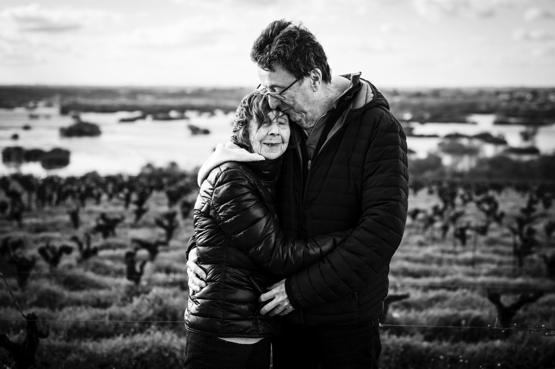 spontaniete-image-noir-blanc la mariée embrasse son époux à la fin de la cérémonie laïque du mariage, en arrière plan les invités applaudissent